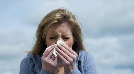 Woman sneezing into a tissue