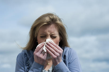 Woman sneezing into a tissue