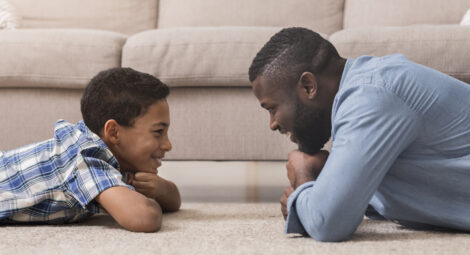 Father and son laying on the ground smiling