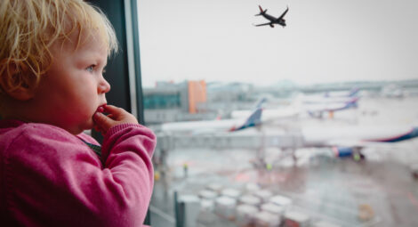 Child at airport looking out the window at planes