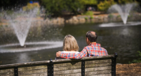Older couple sitting on bench looking at a fountain