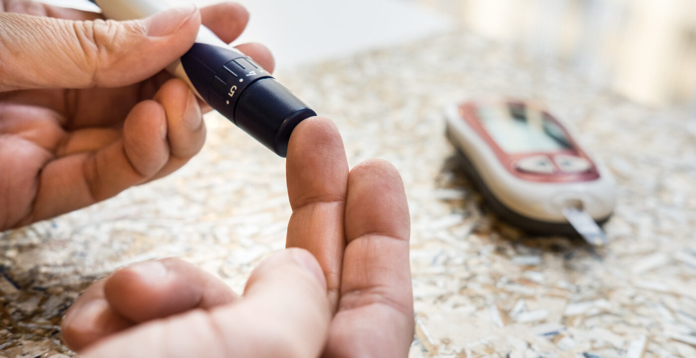 Finger being pricked by a diabetes needle