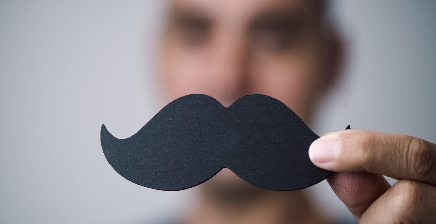 Man holding up a mustache cut out