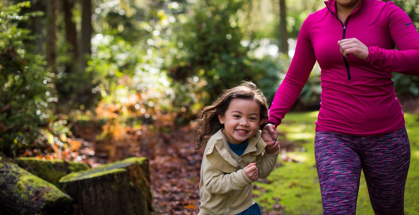 Mother and daughter running through the forest