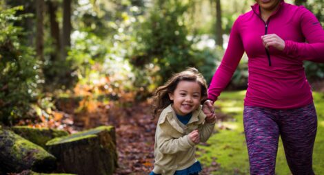 Mother and daughter running through the forest