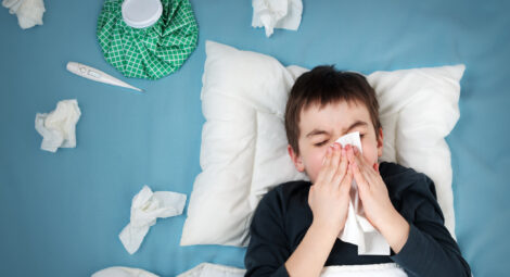 Boy blowing his nose in bed