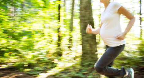 Pregnant woman running throuh the woods.