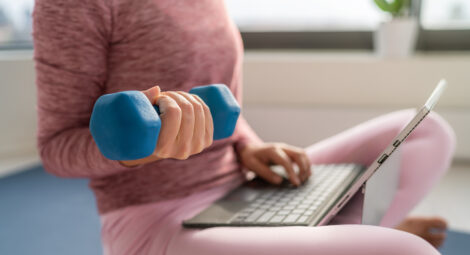 Woman lifting weight and looking on a computer