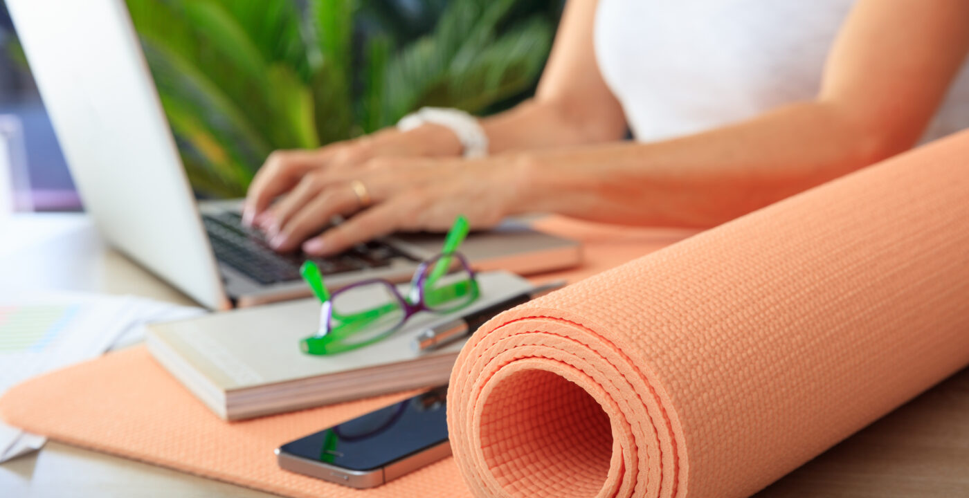 Hands typing on a computer next to a yoga mat