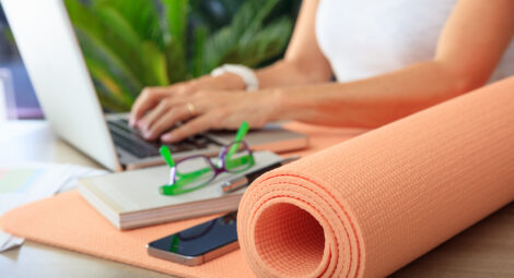 Hands typing on a computer next to a yoga mat