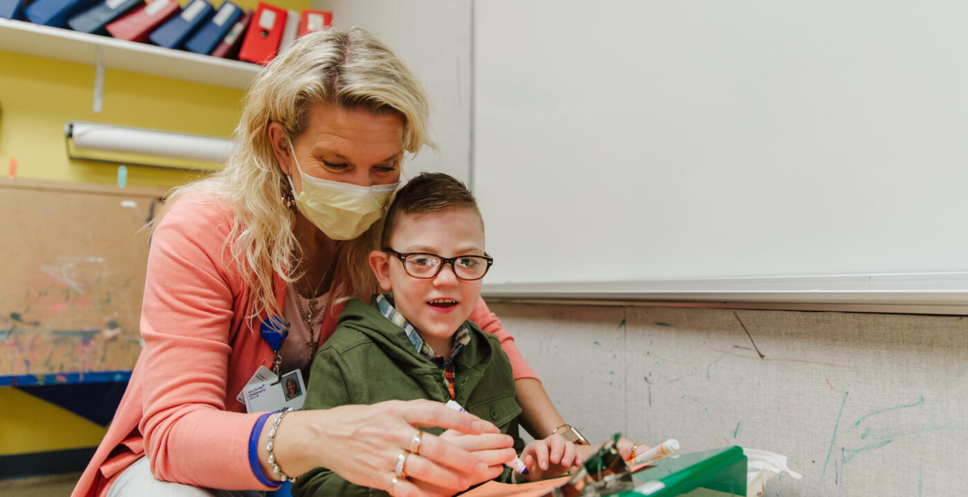 Boy with special needs working on a tool with a hospital worker