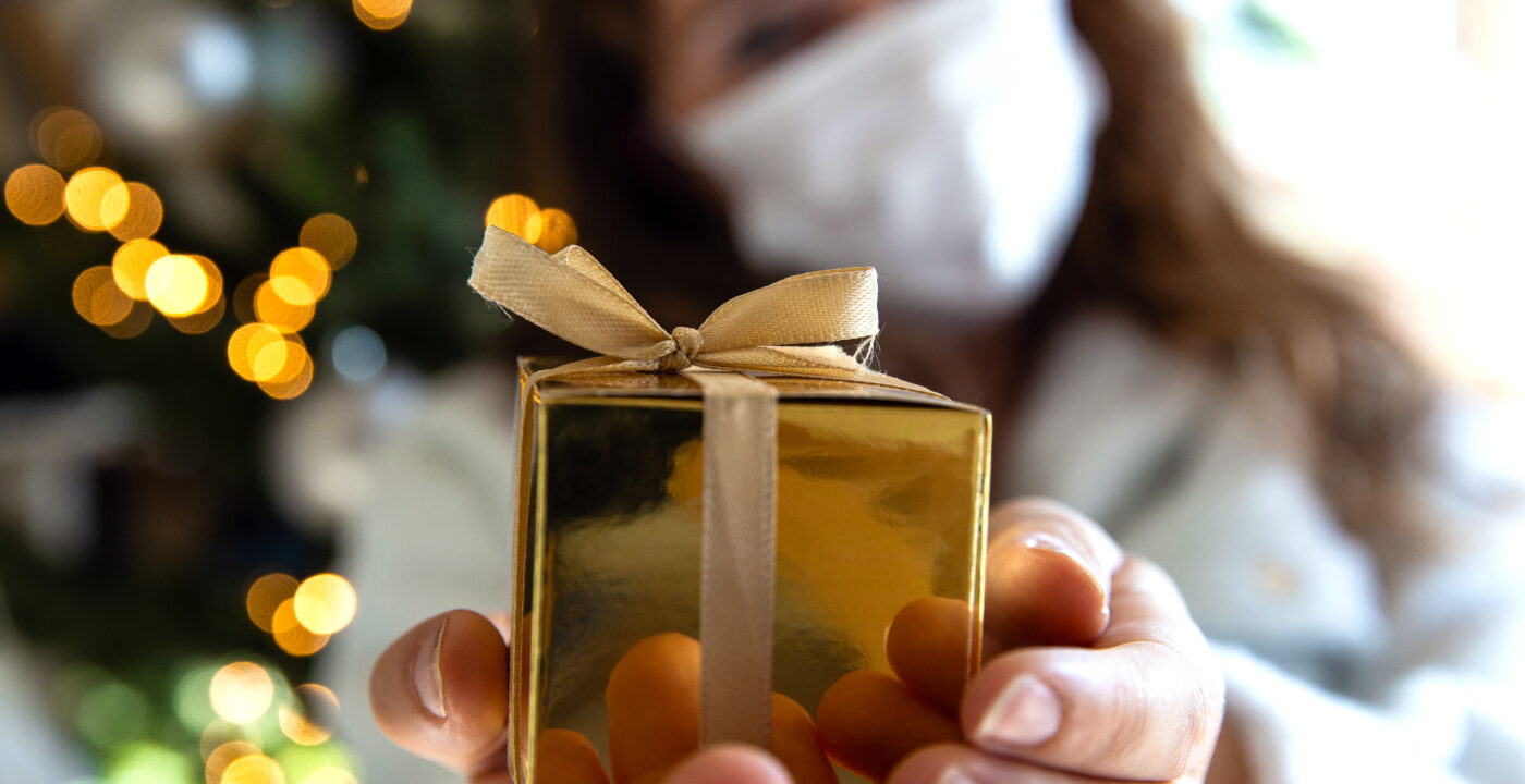 Woman in mask holding up a present
