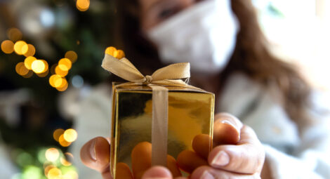Woman in mask holding up a present