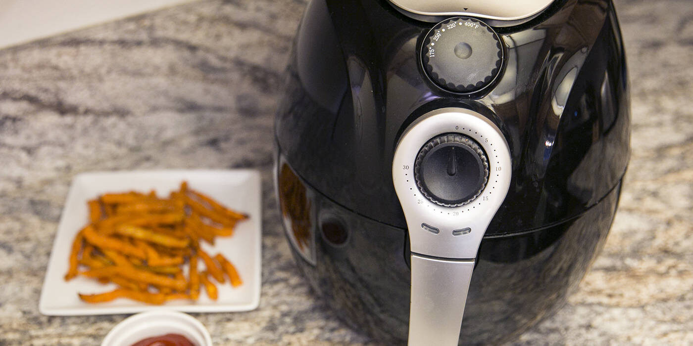 Air fryer on counter with plate of fries