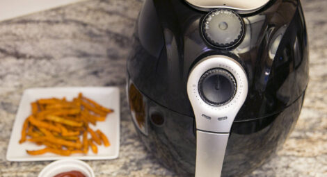 Air fryer on counter with plate of fries