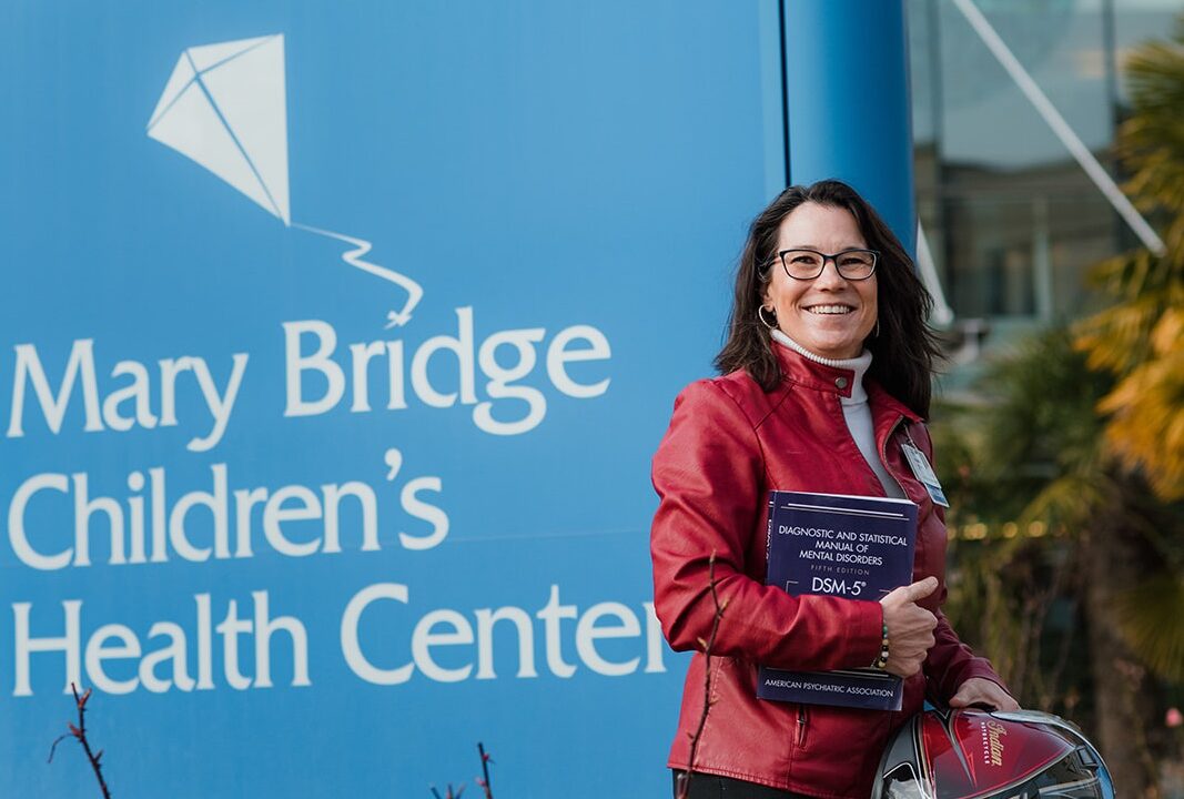 Dr. Ladish smiling in front of a sign