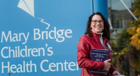 Dr. Ladish smiling in front of a sign