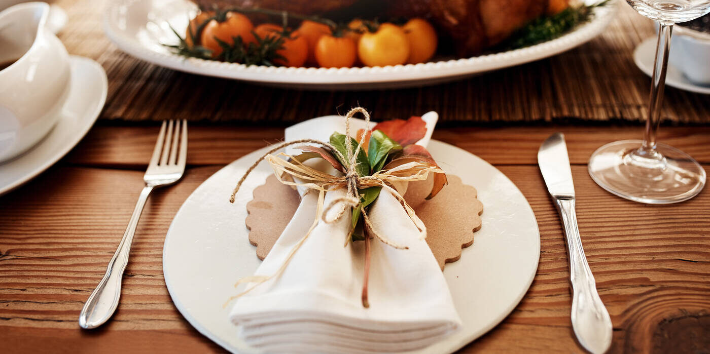 A place setting with colorful leaves tucked into the napkin.