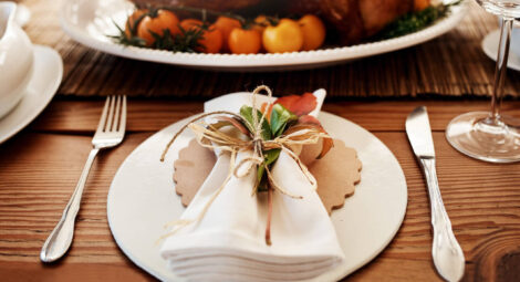 A place setting with colorful leaves tucked into the napkin.