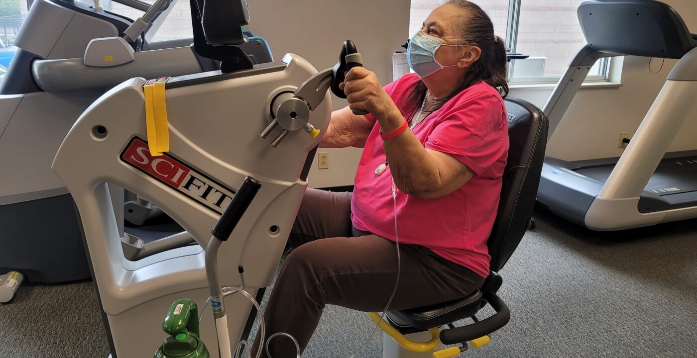Woman on exercise machine hooked up to oxygen