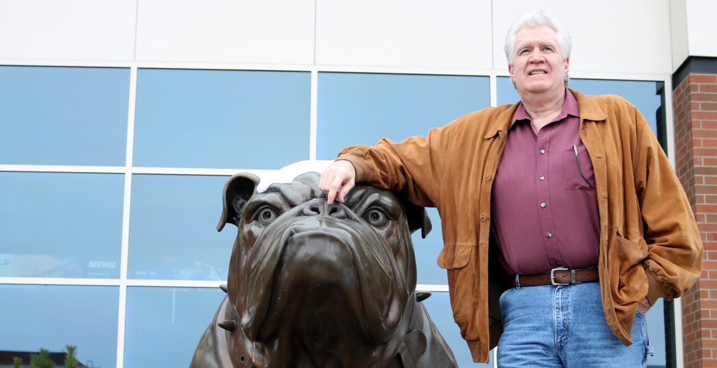 Man posing with a bull dog statue