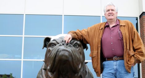 Man posing with a bull dog statue