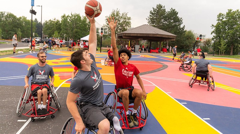 Men playing adaptive basketball in wheelchairs