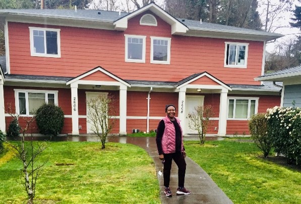 Person posing in front of house.