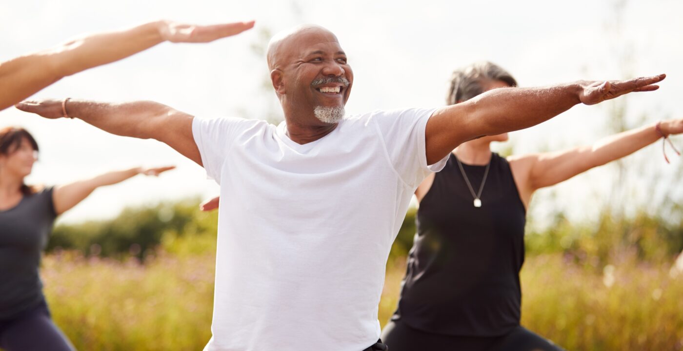 Man doing yoga outside in a group.