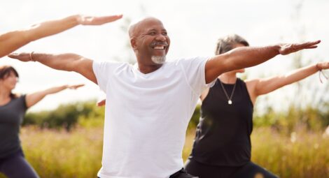 Man doing yoga outside in a group.