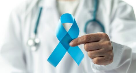 Man with stethoscope holding a blue ribbon.