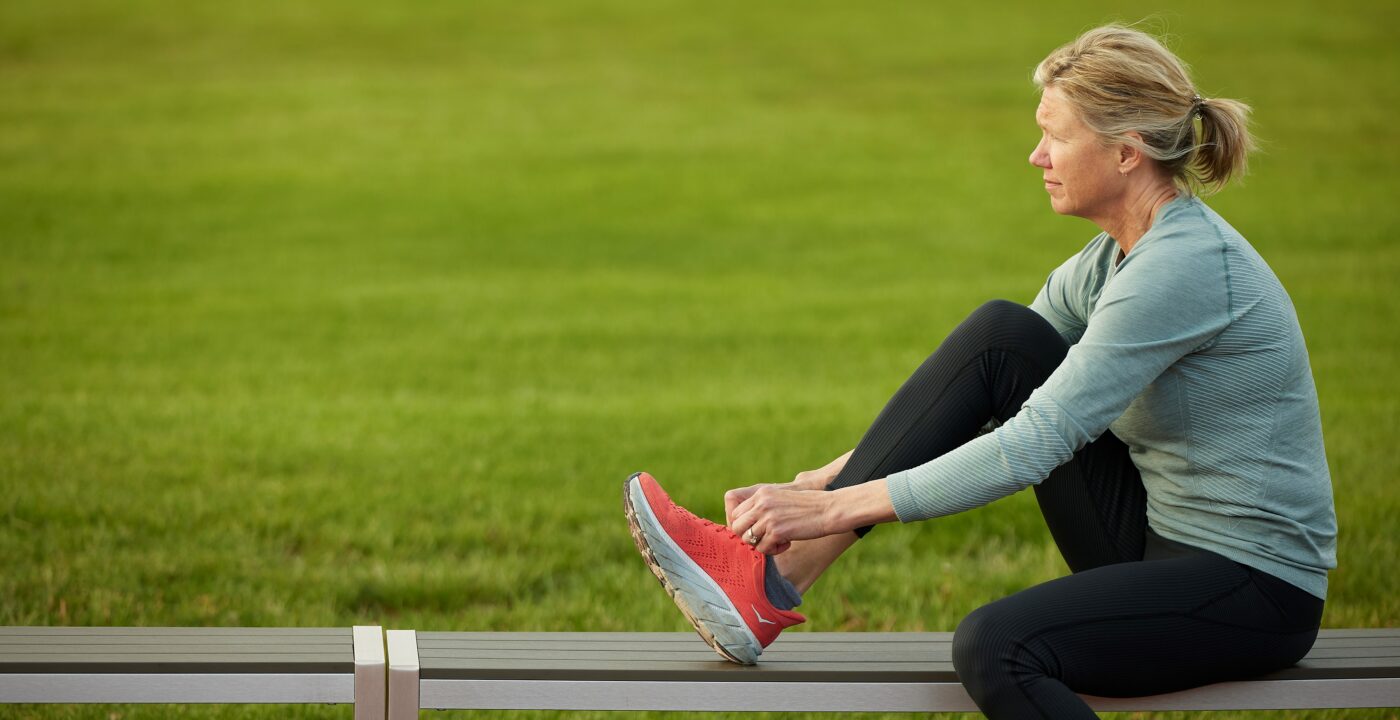 Woman on a bench tying her running shoes.