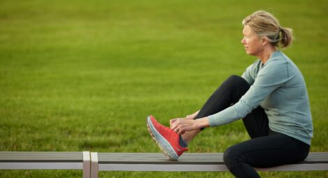 Woman on a bench tying her running shoes.