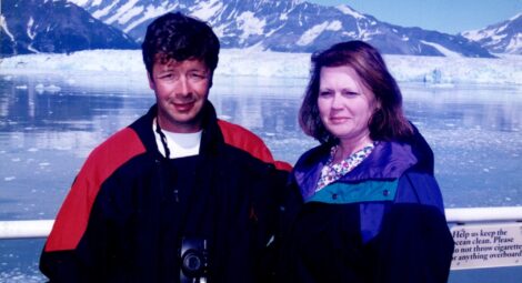 Older photo of a couple posing by a mountain.
