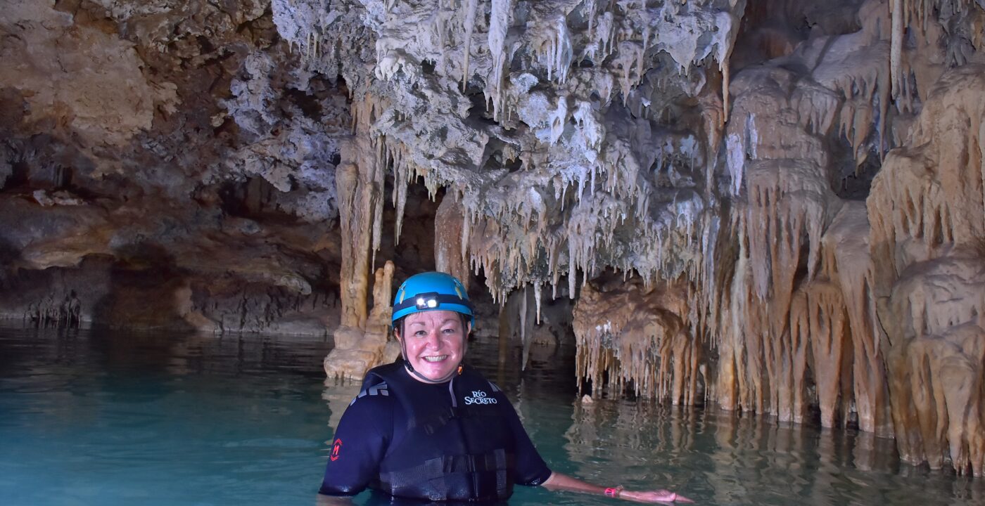 Woman standing in side of a cave filled with water.