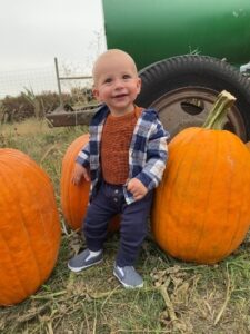 Kid sitting with pumpkins.