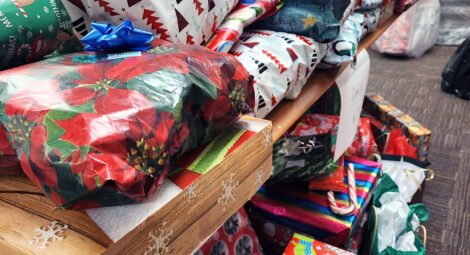 Piles of Christmas gifts stacked on a table in a conference room