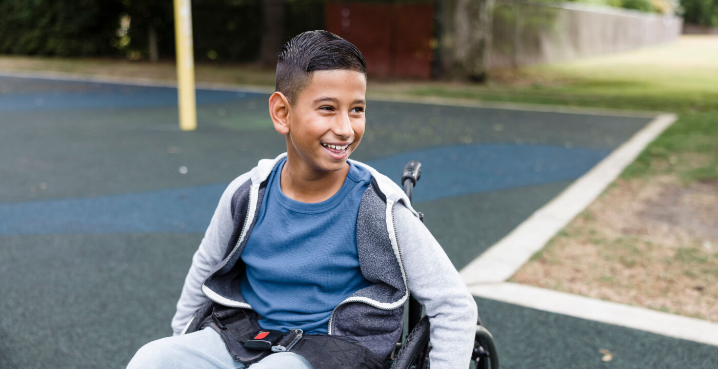 Smiling boy sitting in wheelchair at a park