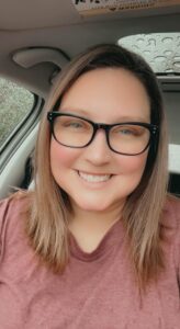 Smiling woman in glasses sits in car