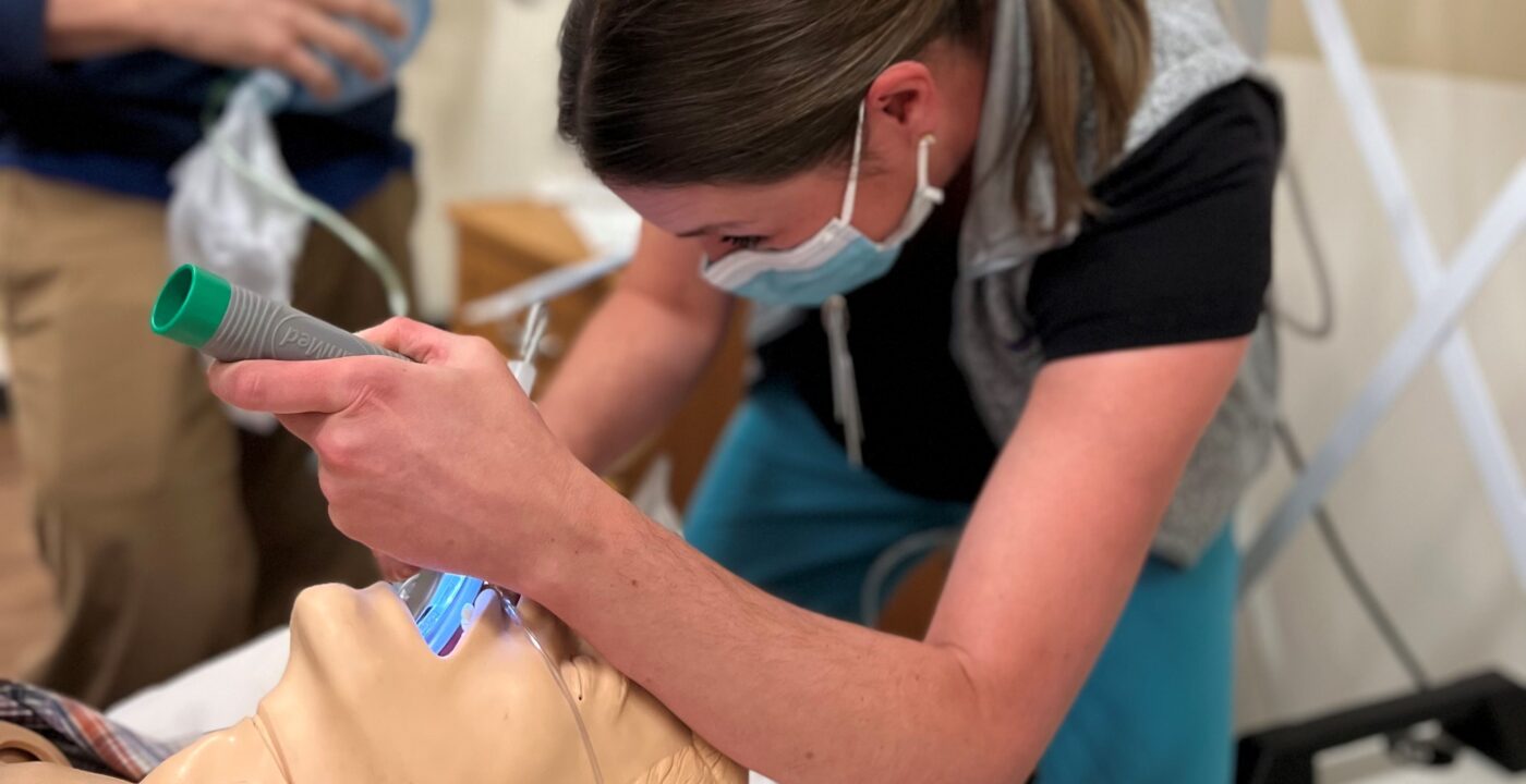 Woman inserts breathing tube into medical manikin