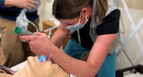 Woman inserts breathing tube into medical manikin