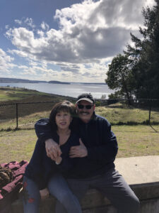 Man and woman sit on a concrete bench at a park overlooking the water