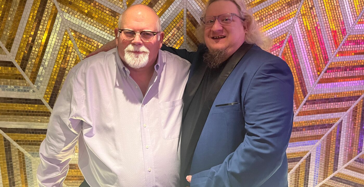 Two men standing in front of a shiny tiled wall