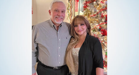 Man and woman pose in front of a Christmas tree