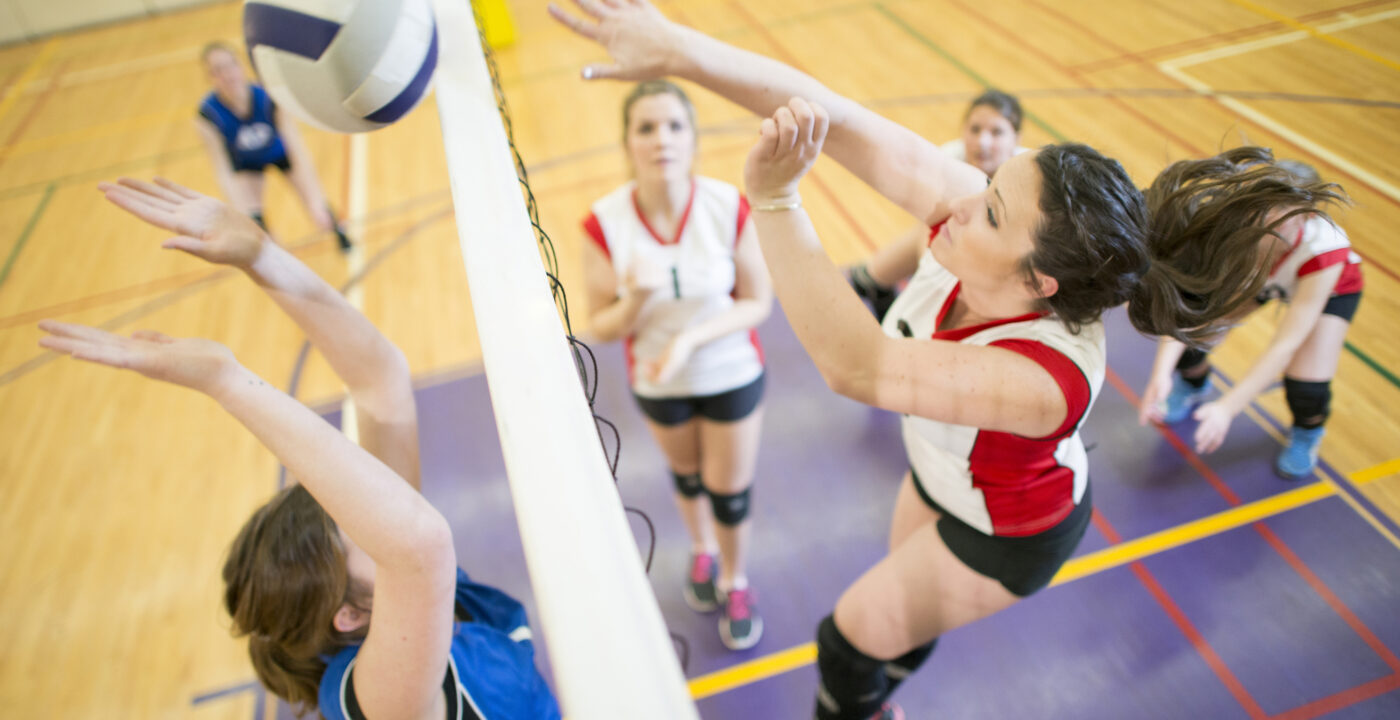 Teenage girl spiking a ball during a competitive volleyball match