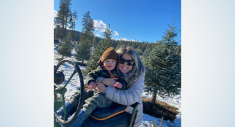 Mom and toddler smile at camera in a sunny woodsy scene