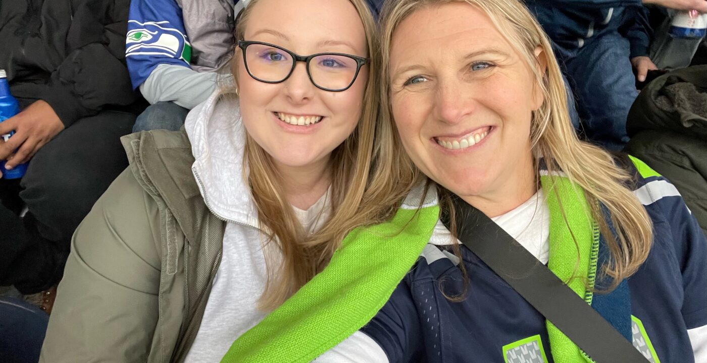 Young adult and adult woman in Seahawks gear pose for the camera