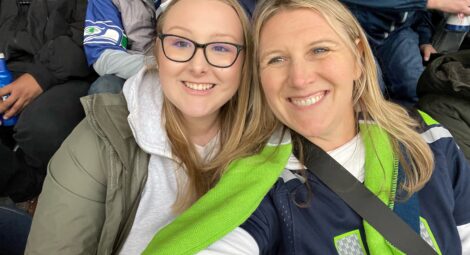 Young adult and adult woman in Seahawks gear pose for the camera