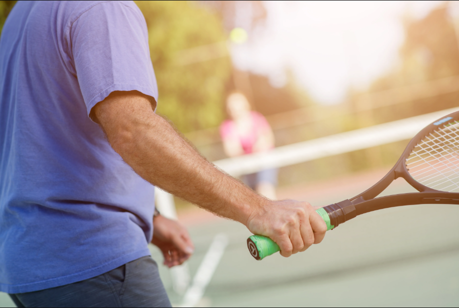 Close-up of man’s arm holding tennis racket