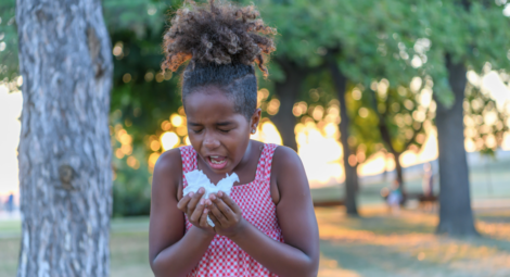 Young girl sneezing into a tissue due to seasonal allergies